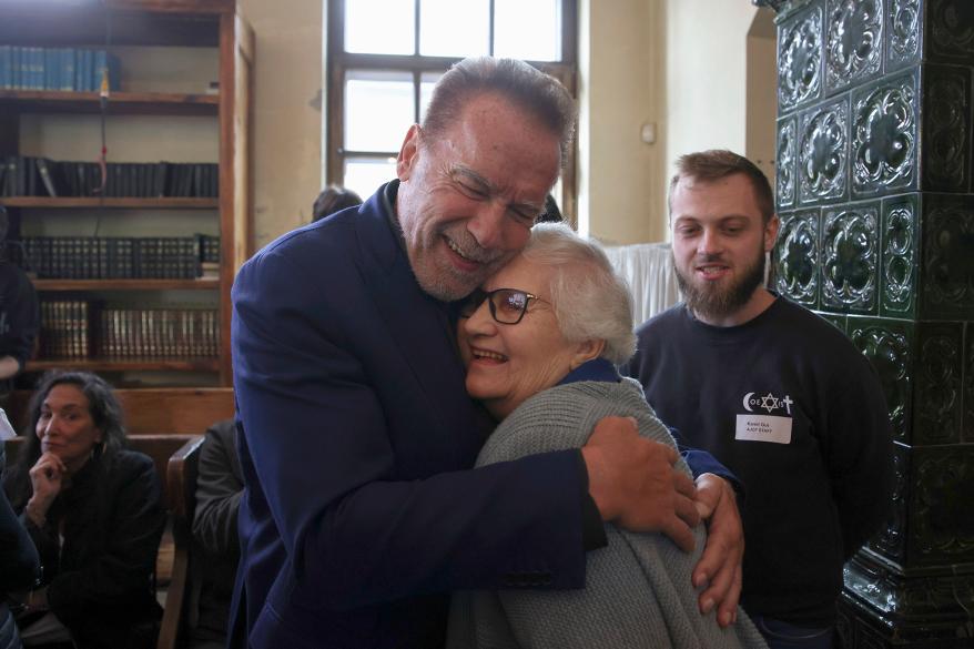 Arnold Schwarzenegger, left, hugs Holocaust survivor Lydia Maksimovicz